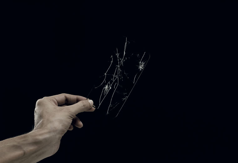 Una mano sosteniendo un móvil con la pantalla astillada